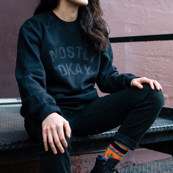 A person wearing a mostly okay sweater sitting on metal stairs