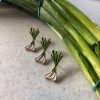 Three green onion pins in front of a bunch of real green onions