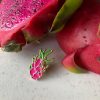 Dragonfruit pin in front of a cut up red fleshed dragonfruit