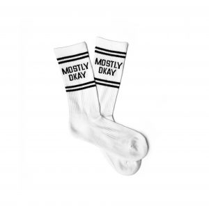 A pair of white crew socks that say "Mostly Okay" on them.
